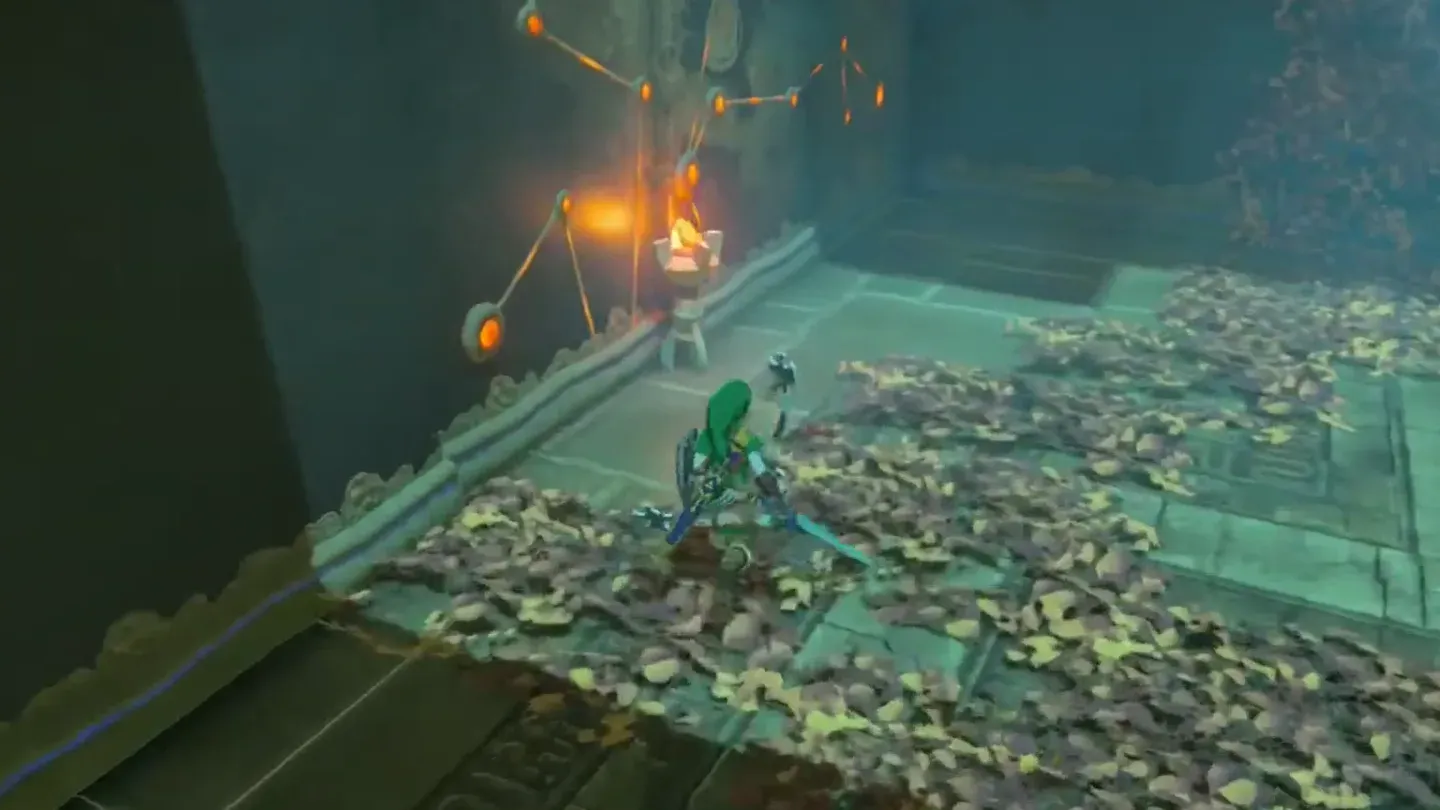Link beside a fallen burning torch on a floor covered in leaves