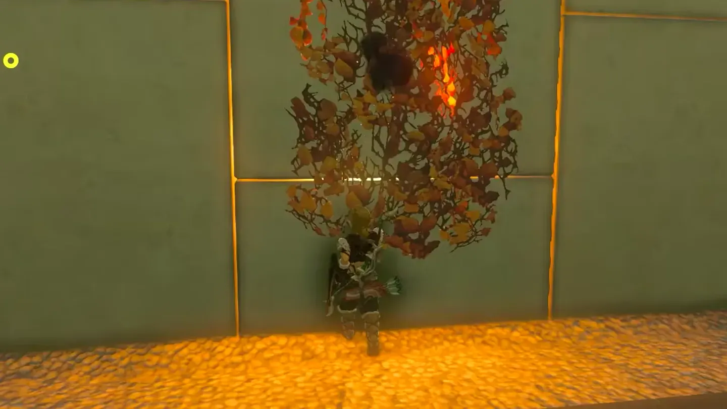 Link holding a lit torch up to the wall of dry leaves