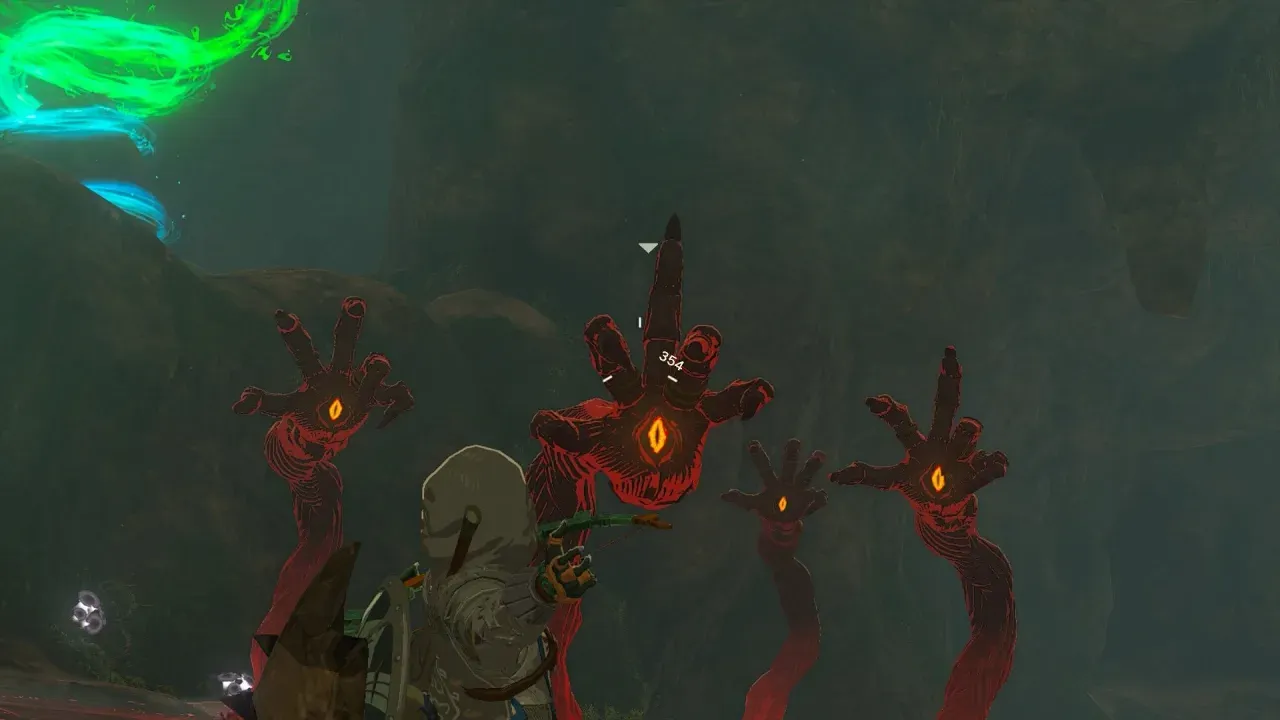 Several red Gloom Spawn hands with a single orange eye each rising in front of Link in a dark cave