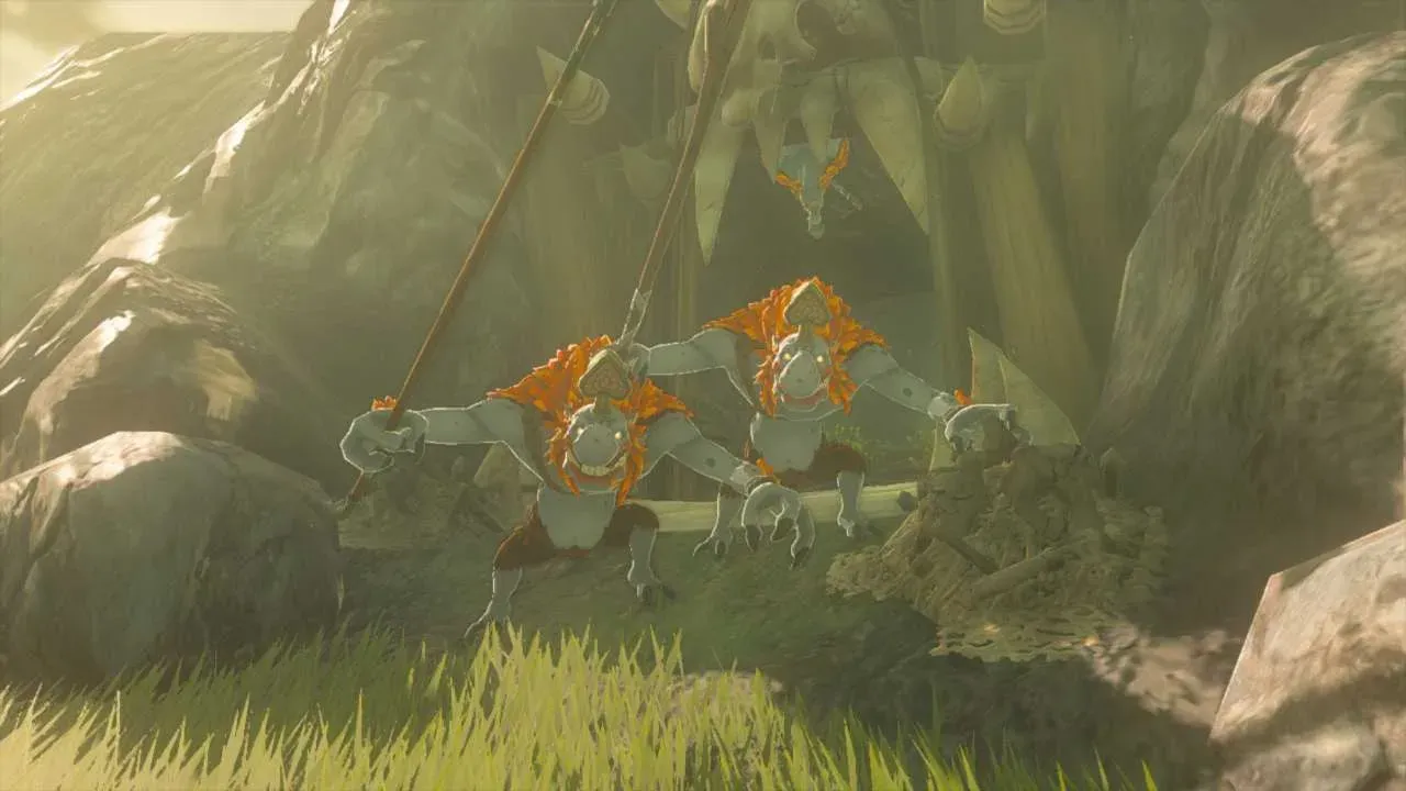 Two red Horriblins with orange manes and spears crouching at a cave mouth while a third hangs upside down from the ceiling behind them