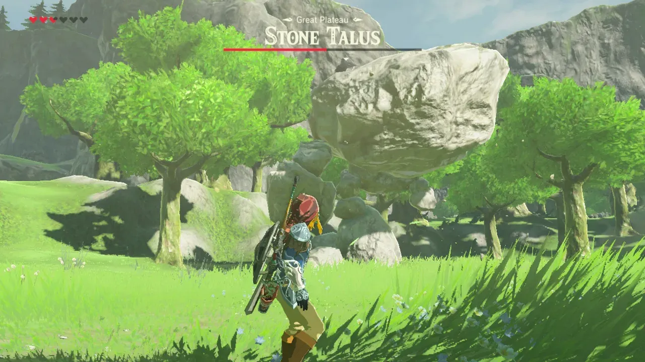 Link facing a Stone Talus in a green field, the boss bar above it